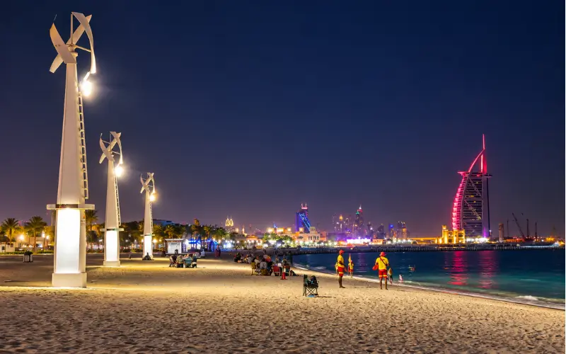 Umm Suqeim Night Swimming Beach Dubai with illuminated beachfront lights and swimmers at night