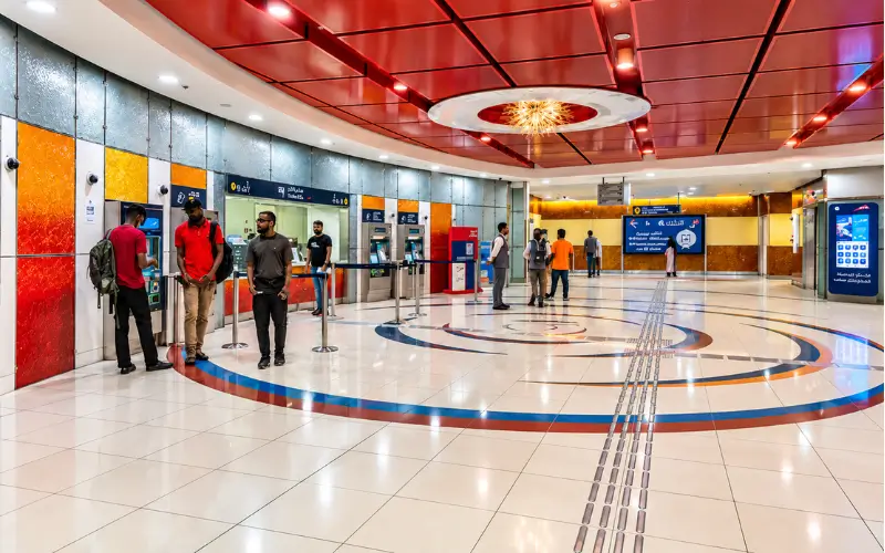 Salah Al Din Metro Station ticket area with passengers using ticket vending machines and Nol card top-up facilities.