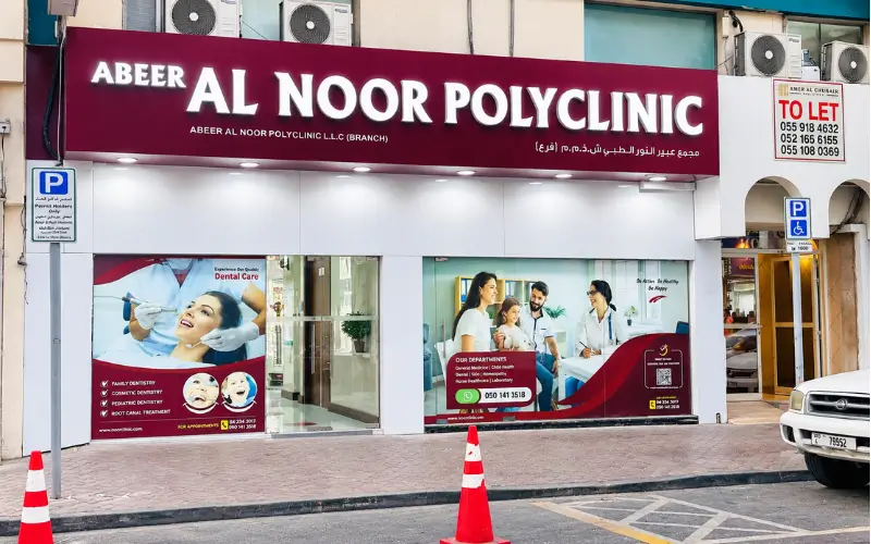 Abeer Al Noor Polyclinic exterior with healthcare service signs, parking area, and storefront entrance.