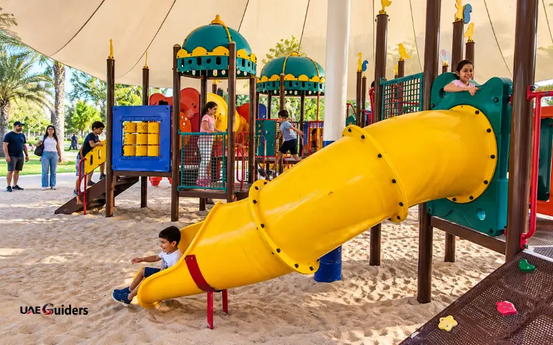 Al Mahatta Park Sharjah children’s play area with a yellow slide and playground equipment.