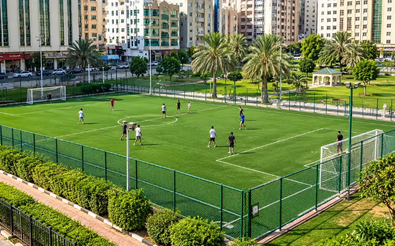 Al Mahatta Park Sharjah football field with green turf and players.