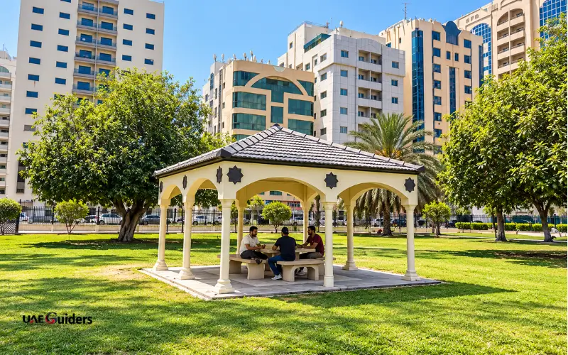 Al Mahatta Park Sharjah green spaces with shaded gazebo and seating benches.